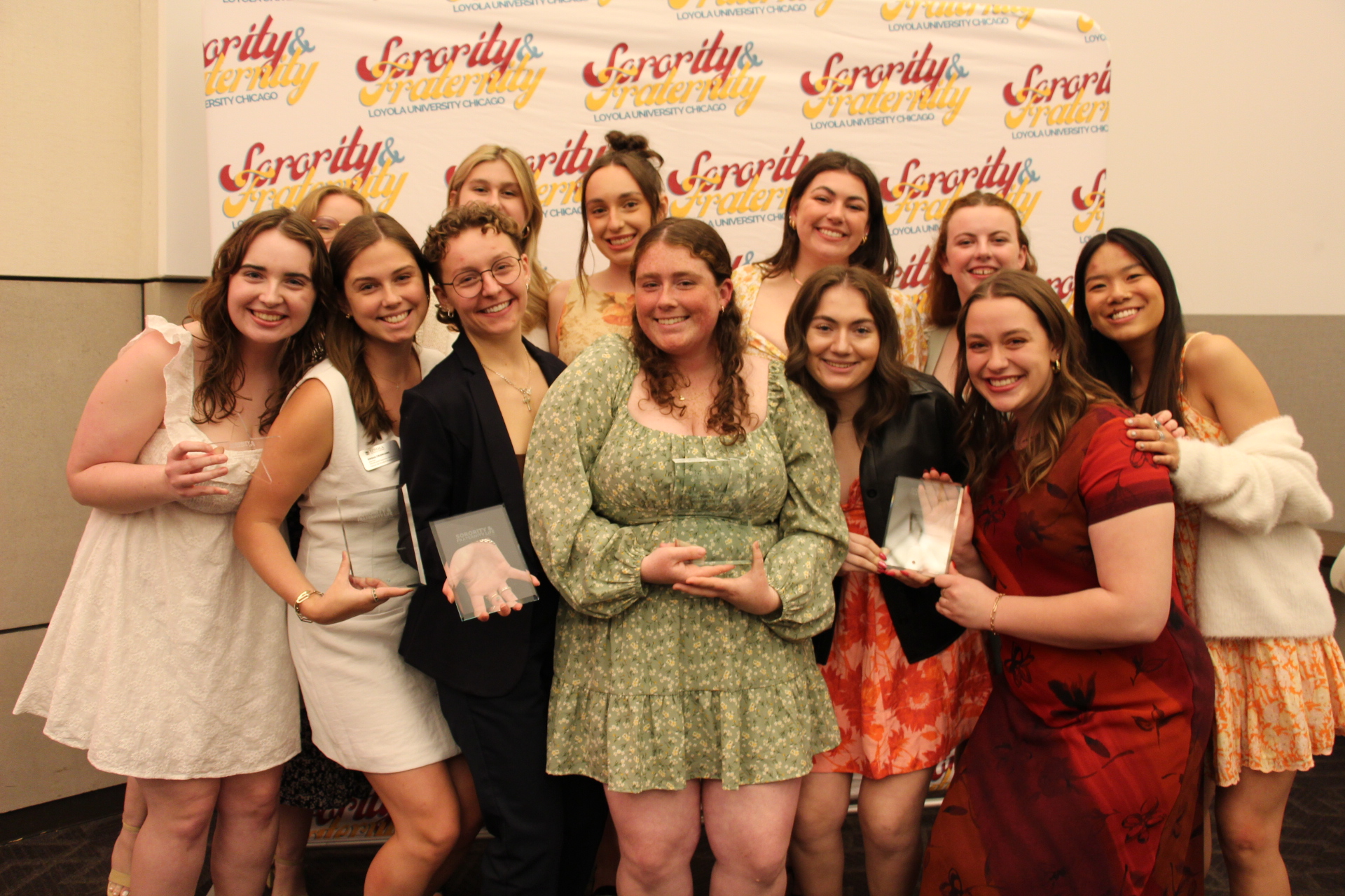 Sorority & Fraternity Life students, member of Kappa Delta, posing for a photo close together holding glass awards in front of a backdrop titled Sorority and Fraternity